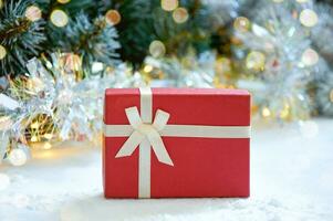 Navidad composición con abeto árbol sucursales, rojo regalo caja y plata oropel en dorado ligero de guirnalda foto