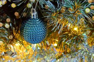 Christmas background with Christmas tree branches, blue ball, silver tinsel in the light of golden garland photo