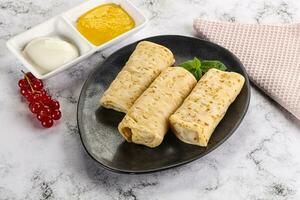 Homemade stuffed pancakes with honey and cream sour photo