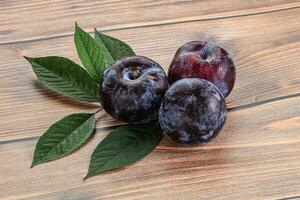 Raw purple plums heap with leaves photo