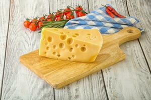 Maasdam cheese piece over board photo