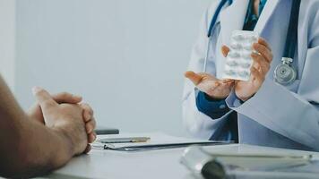 Doctor and patient sitting and talking at medical examination at hospital office, close-up. Therapist filling up medication history records. Medicine and healthcare concept. video