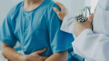 Senior doctor and young male patient who lie on the bed while checking pulse, consult and explain with nurse taking note and supporting in hospital wards. video