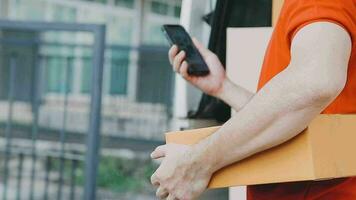 Fast and reliable service. Cheerful young delivery man giving a cardboard box to young woman while standing at the entrance of her apartment video