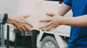 Fast and reliable service. Cheerful young delivery man giving a cardboard box to young woman while standing at the entrance of her apartment video