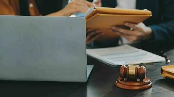 Business and lawyers discussing contract papers with brass scale on desk in office. Law, legal services, advice, justice and law concept picture with film grain effect video