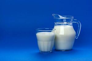 Jar and glass of milk isolated on blue background with copy space for text, dairy product concept photo
