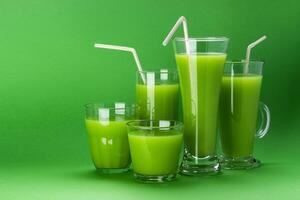 Glasses of green juice isolated on colour green background with copy space photo