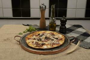 Brazilian pizza with pepperoni, cheese, onion and black olive photo