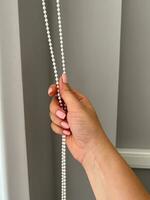 A female hand holding a beaded chain for the blinds photo