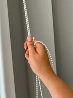 A female hand holding a beaded chain for the blinds photo