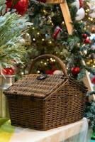 de cerca ver de un picnic cesta en el mesa con Navidad árbol como antecedentes foto