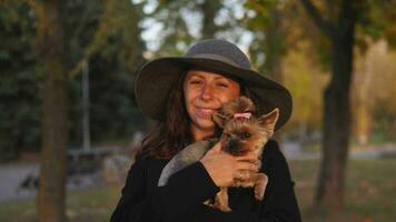 sensitive portrait of a stylish woman in a large hat and a small Yorkie dog in her hands video