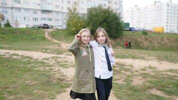 Two little girls sisters walk down the street together and hug and smile video