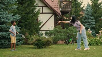 Caucasian mom plays badminton with her African son on the lawn near the house.Mother's Day. video