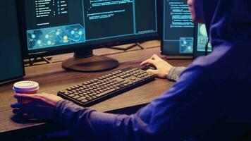 joven hacker Bebiendo café mientras corriendo spyware software diseñado a reunir información desde los usuarios ordenadores sin su conocimiento. guión niño haciendo ilegal cosas en pintada pintado escondite video