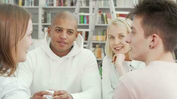 Diverse group of college students laughing and talking at the library video