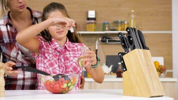 Jeune fille verser pétrole dans salade dans une verre bol dans le cuisine. lent mouvement 4k métrage video