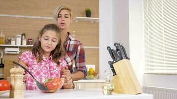 liefhebbend moeder helpt haar dochter naar mengen een salade in een glas kom Bij de keuken. dolly schuif 4k langzaam beweging beeldmateriaal video