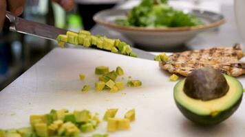 Cook in kitchen cutting an avocado in pieces on a cutting board in restaurant video