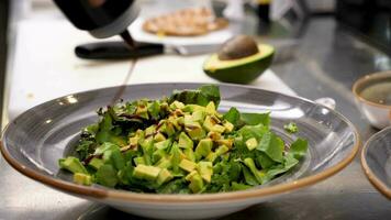 mannetje handen gieten souce en kruiderij avocado salade in restaurant keuken video