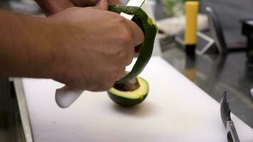 Close up of cook hands peeling an avocado in restaurant kitchen video