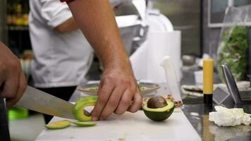 Cutting avocado in pieces on a cutting board in the kitchen video