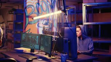 Teamworking hackers in graffiti painted hideout targeting vulnerable unpatched connections, seeking to compromise digital devices and steal valuable sensitive information from them video