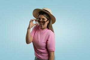Woman in Casual Clothing and Straw Hat Standing on Colored Background photo