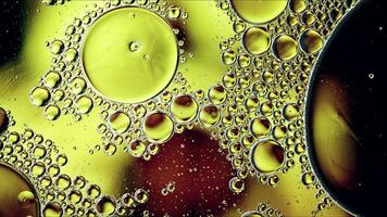 El aceite de comida colorido abstracto cae burbujas y esferas que fluyen en la superficie del agua foto