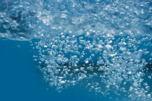 agua Azul burbujas en el superficie ondas desenfocar borroso transparente blanco negro de colores claro calma agua superficie textura con chapoteo y burbujas agua olas con brillante modelo textura antecedentes. foto