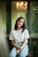 toothy smiling face of asian teenager sitting on wood desk photo