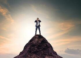 business man and binocular lens standing on top of mountain and looking through for serching photo