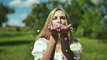 The girl blows colorful paper confetti out of her hands. video