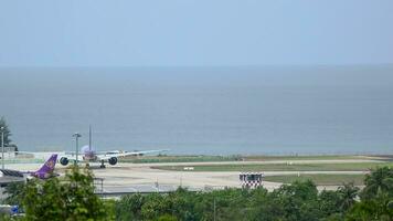 phuket, Tailândia novembro 17, 2014 corpo largo passageiro avião boeing 777 do tailandês vias aéreas em a aeródromo às phuket aeroporto. aeronave taxiando em a pista. pista e mar fundo video