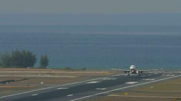 PHUKET, THAILAND FEBRUARY 13, 2023 Airplane Airbus A320, HS TXM of Thai Smile landing and touching at Phuket airport, spoilers up, speed down. Runway and sea background video