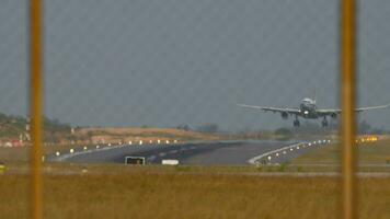 lento movimento metraggio di un aereo con un irriconoscibile livrea, approdo, toccante e frenata. Visualizza di il pista di decollo attraverso il aeroporto recinzione. pista d'atterraggio illuminato con atterraggio luci video