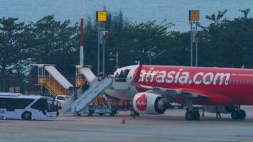 PHUKET, THAILAND FEBRUARY 27, 2023 People board an AirAsia plane at Phuket airport. Asian Low Cost Aircraft on the tarmac near the terminal video