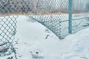 Hole in wire border fence. Illegal trespassing. Escape from prison or closed institution for mentally ill. Maximum security detention facility. Winter snowy weather. photo