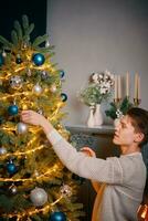 chico sonriente decorando el árbol de navidad. foto