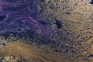 Fluid Art. Golden metallic particles and violet waves. Marble effect background or texture photo