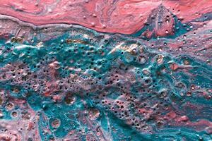 Fluid Art. Embossed mixing, craters and drips of pink and turquoise paint. Marble effect background or texture photo