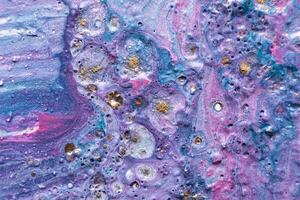 Fluid Art. Embossed mixing, craters and drips of violet paint. Marble effect background or texture photo