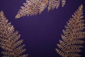 Christmas violet background. Shining golden floral frame made of leaves photo