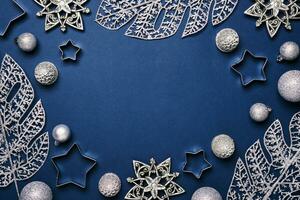 Christmas blue background. Shining silver pattern frame made of frost decorative leaves and baubles photo