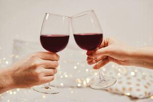 Hands of a man and a woman are holding glasses of wine. Romantic atmosphere, soft focus, bokeh, close-up photo