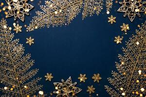 Christmas blue background. Shining golden pattern frame made of leaves, stars and snowflakes photo