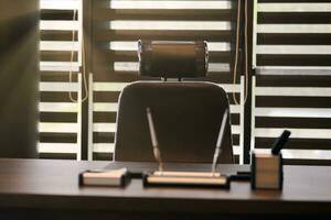 Business office workplace. Sunlight at work place for chief, boss or other employees. Table and comfortable chair. Light through the half open blinds photo