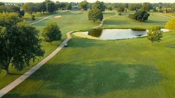 Beautiful golf course with green grass, trees, lake on a sunny day. Aerial view of a green golf course. Flying over the golf course. video