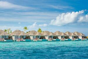 vista aérea de la isla de maldivas, resort de lujosas villas acuáticas y muelle de madera. hermoso cielo y fondo de la playa de la laguna oceánica. concepto de vacaciones y viajes de vacaciones de verano. paraíso aéreo paisaje pano foto
